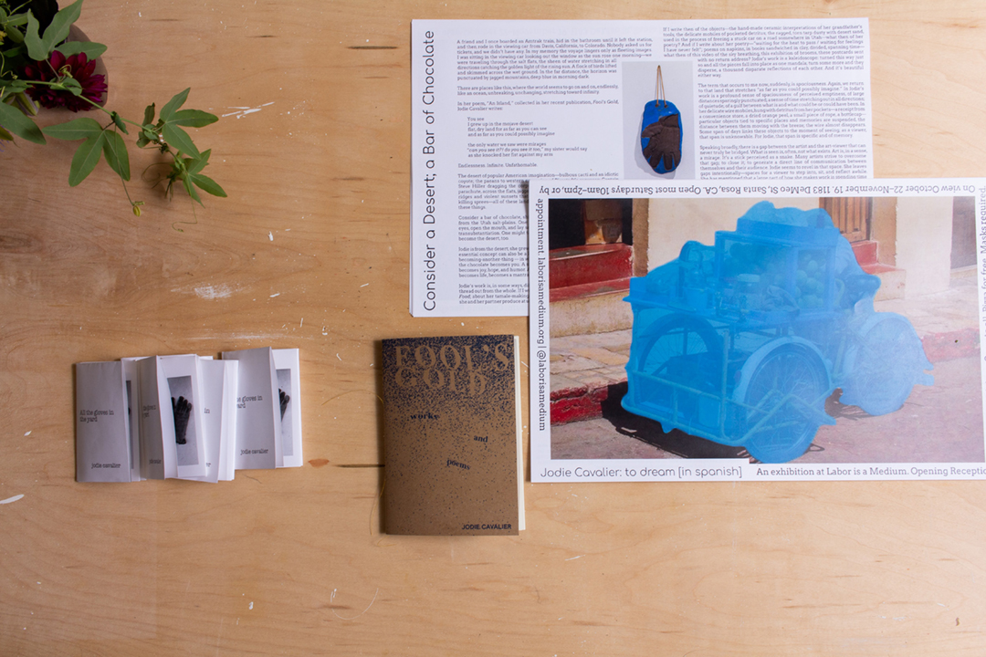 A blue wall with several objects including a wooden bench, silver milagros, a cassette player, paintings of candles, an aloe plant, tools, and more.