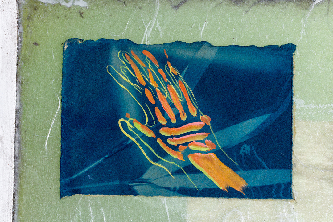 A detail of a small gouache drawing of a hand and hovering bones